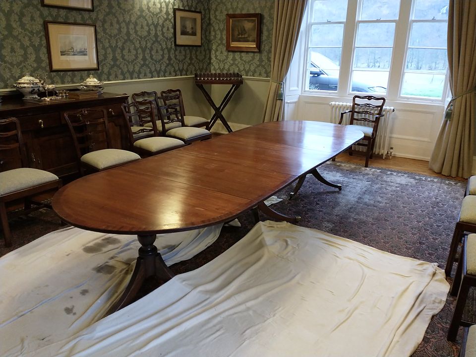 Twin pedestal D-end dining table in the client's dining room on dust sheets, before restoration