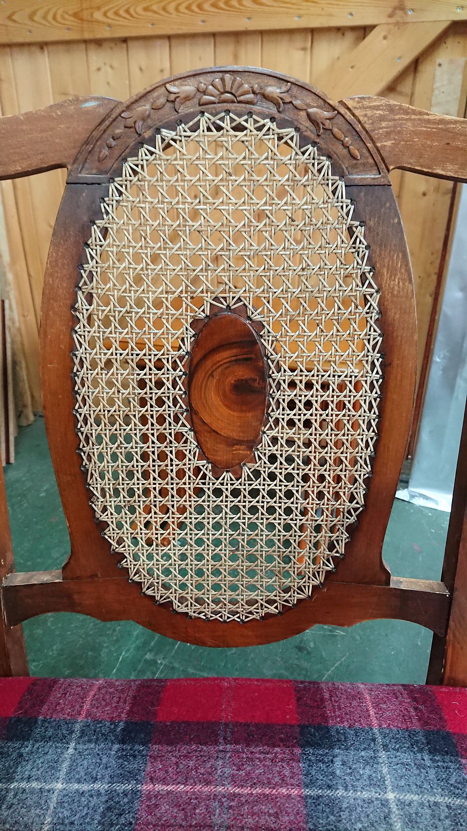 Oval chair back with hand-woven cane and a carved crest rail, around a figured centre panel